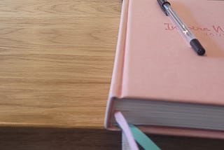 A notebook and pen sitting on top of a table.