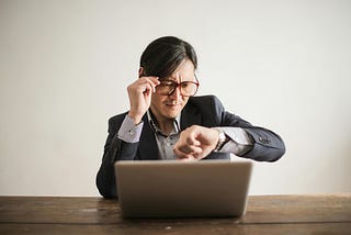 Confused businessman checking time on wristwatch