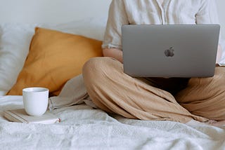 Woman using laptop sitting in bed.