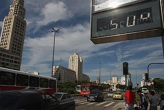 Um relógio de rua marca a temperatura de 50 graus. À esquerda está o prédio da Central do Brasil, no Rio de Janeiro.