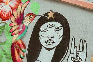 Street art in Sao Paulo of woman with three eyes and holding up a hand with an eye on the palm