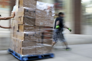 Workers moving boxes in warehouse.