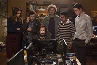 A screen shot having the main cast of the show gazing on a desktop screen.