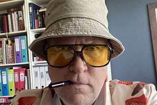 Photo of Rob in his Hunter S Thompson bucket hat and big glasses.