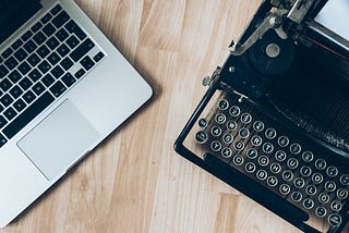 A new laptop on the left and an antique typewriter on the right