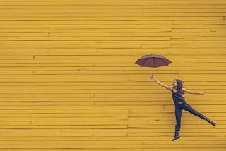 young woman holding an umbrella appearing to be lifted in the air