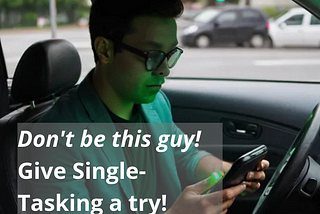 Image of person sitting at traffic light with the green light of his signal shining on his face while he’s holding his cell phone and looking at it instead of paying attention to traffic. Caption stating, “Don’t be this guy! Give Single-Tasking a try!”