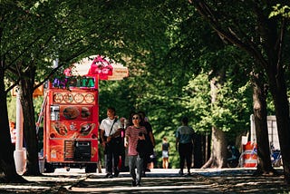 Asian lady walking down a side walk under some trees