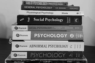 A black-and-white photo of a stack of psychology books, including titles on child psychology, social psychology, abnormal psychology, and general psychology.