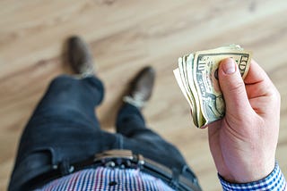 Man holding a wad of $10 bills