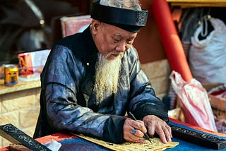 An old man who is writing on a paper.