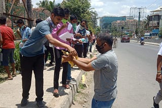 A citizen in Bangalore providing refreshment to migrant workers waiting for their vehicle to go to their village.