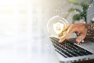 A businessman works on his laptop at home with a virtual display showing a symbol to signify cyber security privacy and online data protection.