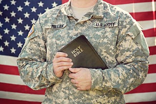 Army man before a U.S. flag holding a Bible