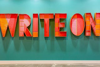 Vivid orange metal sign saying “Write On”. Editor program on Medium.