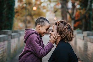 Small boy affectionately holding the face of his mother