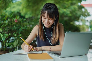 Smiling woman taking notes in front of her computer