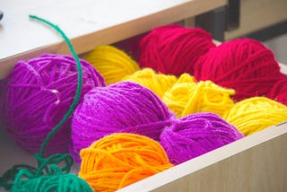 Open drawer with balls of yarn arranged by color.