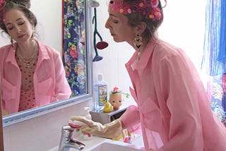 Alex Mitchell cleaning bathroom sink, all dressed up in pink with her misfit attitude about feeling fab whenever she wants.