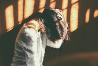 Woman holding her head in her hands in distress.