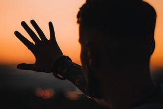 man showing one hand at sunset