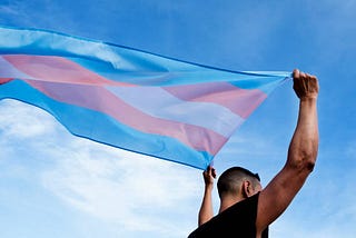 A trans man holding up a Transgender flag