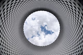 Matrixed gray and white tunnel overlooking a white cloudy and blue sky