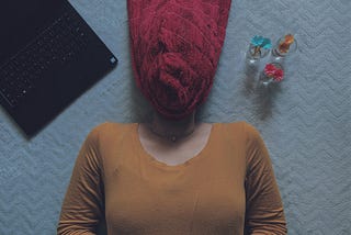 Photo of woman in brown long sleeve shirt with face wrapped in towel.