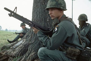 A soldier in the 101st Airborne Division holding a M60 Machine gun beside a tree during the Vietnam war.