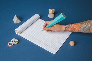 A person writing on a notepad with an art-deco pen