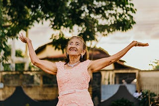 Older woman dancing with two arms up.