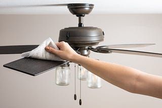 How can you clean a ceiling fan without taking it down from the roof or using an electric broom?