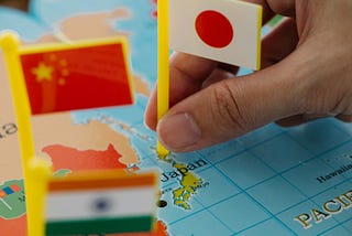 Bandeirinhas da China e Japão sendo colocada num mapa mundi — Diferença entre chinês japonês e coreano