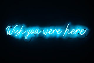 Blue neon sign saying “Wish you were here”