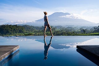 Woman standing at the edge of a swimming pool looking reflectively into the distance