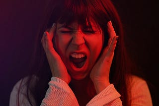 Woman, aggression, hands on temples mouth open to scream, red filter