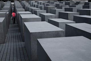 In the distance, a person is walking through the 2,711 concrete slabs, arranged in a grid pattern.