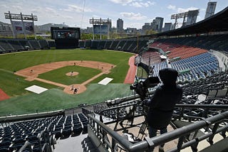 A broadcast camera operator shoots video in an empty stadium.