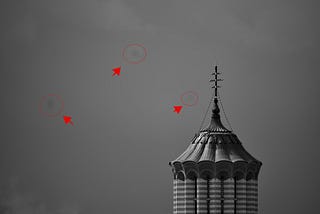 Photo of a cathedral’s tower, with three dust particles from the camera’s sensor.