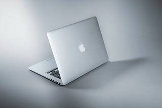 A gray MacBook on a gray background.