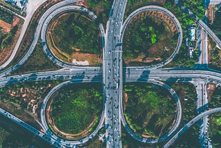 Photo of a highway with intersections taken from a drone view from the sky. The image intends to reflect an analogy of a complex system