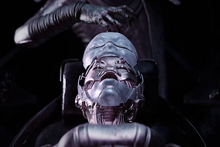 A robotic hand reaching out over a robotic face.
