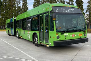 A green articulated TriMet FX bus parked at its layover spot in Gresham.