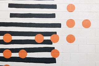 Photo of a pattern of horizontal black lines disrupted by orange dots