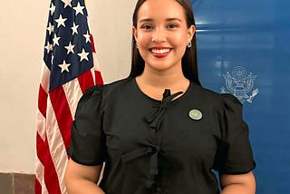 Global UGRAD student poses in front of an American flag on a standing pole.