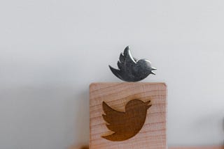 Wood carving of the Twitter logo, with a metallic bird on top