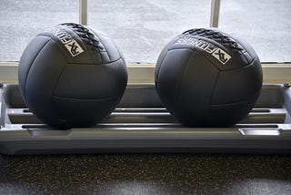 Two fitness balls sitting on a rack in a gym