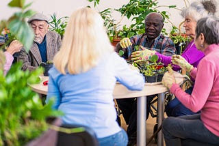 Grupo de personas adultas mayores sembrando plantas