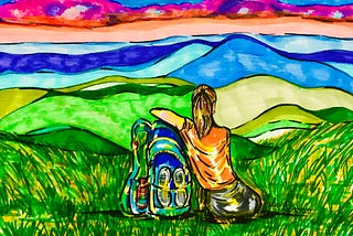 A girl resting in a grass meadow looking at the mountains.