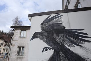 A mural showing a raven with a clockwork in his feathers on a white wall.